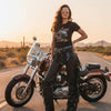 Woman wearing black fringe leather chaps beside a cruiser motorcycle