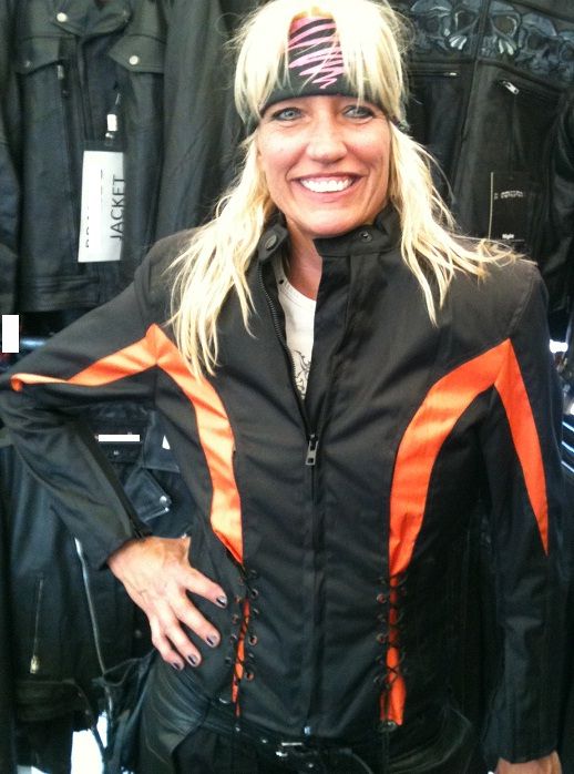 Women textile motorcycle jacket by Dynamicleather in vibrant orange, featuring a fitted design and protective padding.