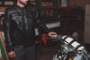 Black men's Raider jacket by Dynamicleather featuring a sleek design and button closure, shown on a hanger.